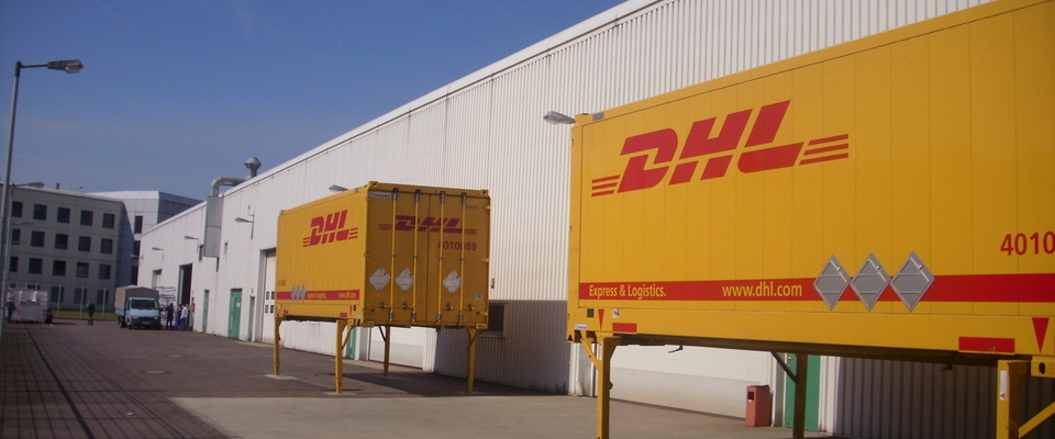 2 gelbe Seecontainer der DHL vor der Werkhalle